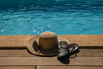 Chapeau et lunettes au bord de la piscine ensoleill&eacute;e