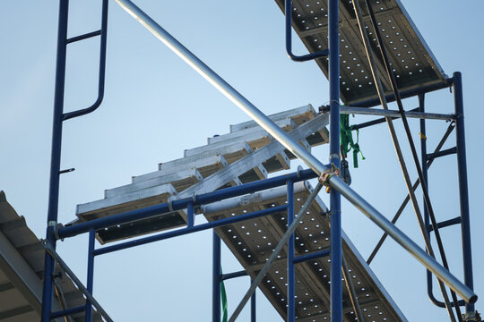 Scaffolding structure with stairway for going to higher floor for working at height such as the roof top. Industrial building and construction site workplace.