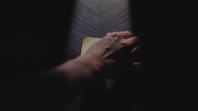 Slow motion close up footage of a hand writing out Notes with bullet points to be filled in on a paper note and placing it on a table. Shot in dramatic lighting for an impressive title or transition.