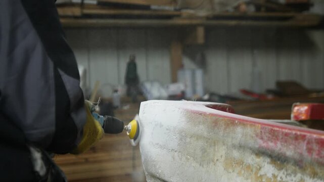 Sanding polyester filler on fiberglass boat with orbital sander