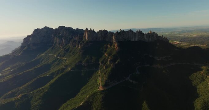 Continuous drone orbit at conglomerate needles of the Montserrat massif, transitioning from the Santa Maria abbey to the panoramic vistas of the Llobregat valley, Catalonia, Spain