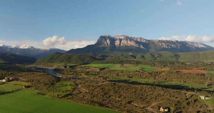 Aerial Gliding over the Sobrarbe highlands near Ainsa, where the iconic limestone face of Pe&ntilde;a Monta&ntilde;esa stands as a prehistoric sentinel over the rugged Aragonese Pyrenees.