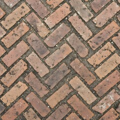 Paving stones arranged in a herringbone pattern on a walkway in an outdoor setting during daylight hours