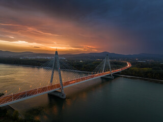 Budapest, Hungary - Aerial view of the cable-stayed Megyeri Bridge over River Danube at dusk with beautiful dramatic golden sunset sky and Buda Hills at background