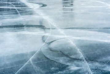 Ice skating marks on frozen blue surface in winter light