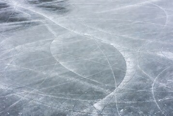 Ice skate trails on textured frozen surface in winter daylight