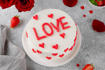 Vanilla strawberry cake with small red hearts for Valentine's day on a white plate on a gray concrete background. Romantic cake.