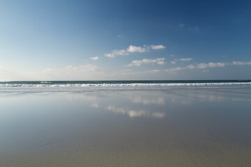 Minimal beach with wet sand reflection and clear horizon &mdash; calm seascape with copy space