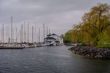 Sailboats docked at marina beside clubhouse on overcast day
