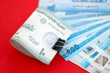 United Arab Emirates dirham money bills in big amount close up on red. Finance and banking concept