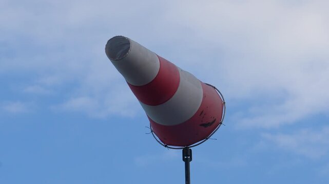 Red and white strip windsock on blue sky background. The equipment using to indication windy speed and direction.