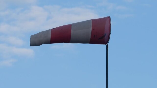 Red and white strip windsock on blue sky background. The equipment using to indication windy speed and direction.