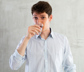Young guy posing with glass of water in studio