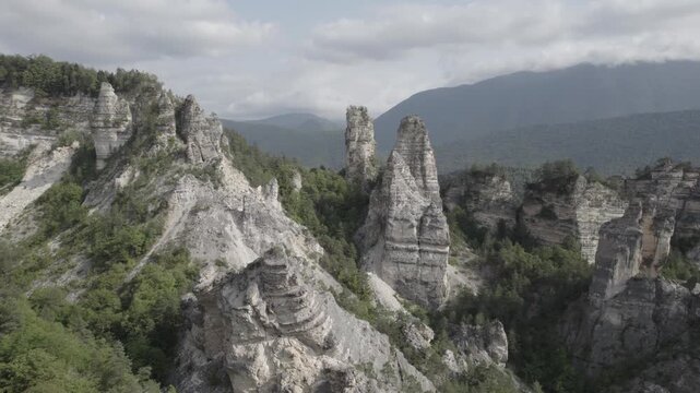 Aerial drone shot circling the Sairme Pillars in Lechkhumi, Georgia, capturing towering rock formations from all sides amid green hills and untouched Caucasus nature. High-quality 4K footage.