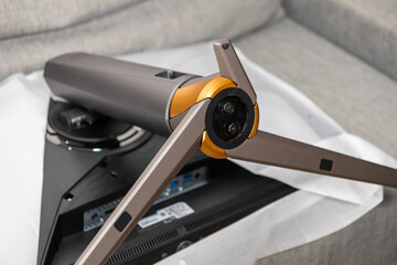 Modern gray and orange gaming monitor stand being unboxed, showcasing its unique design and rear connectivity ports for a new technology setup