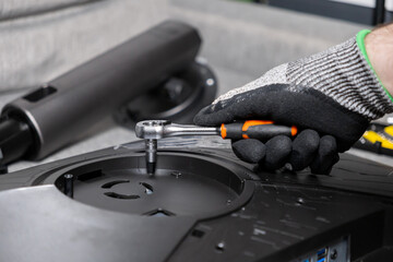Gloved hand precisely using a ratchet wrench to assemble or repair electronic equipment, symbolizing meticulous maintenance, technical support, and professional service