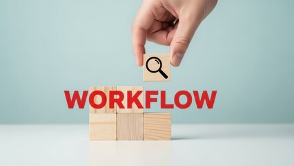 Hand placing magnifying glass icon on wooden blocks spelling the word workflow for process optimization and business analysis concept