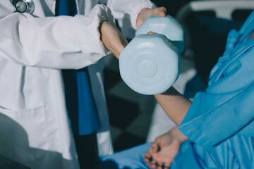 Physical therapist assisting a woman with dumbbell exercise