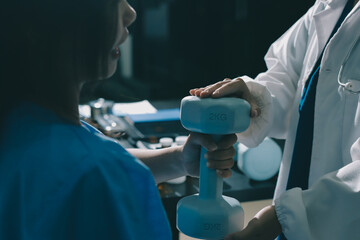 Physical therapist assisting a woman with dumbbell exercise