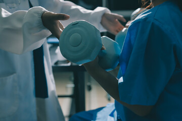 Physical therapist assisting a woman with dumbbell exercise