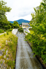 View of the Riegerbach stream in Millstatt and the surrounding green landscape.
