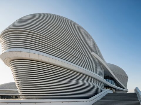 Modern curved building with a unique design and blue sky background - Powered by Adobe