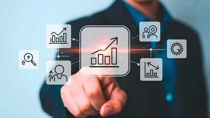 Businessman touching a futuristic digital interface displaying various business icons, symbolizing strategic planning, growth, and data analysis in a modern corporate environment