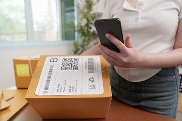 Small Business. Woman managing packages and using smartphone for logistics.