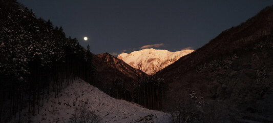 幻想的な夜明け前のコールドムーンと雪の谷川岳