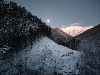 朝日に照らされる雪の谷川岳とコールドムーン
