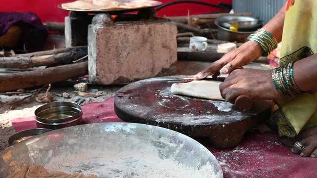 A close-up shot of a traditional Indian chapati being cooked on a clay stove and griddle in a rural village kitchen. This image represents authentic Indian culture, rural happy lifestyle