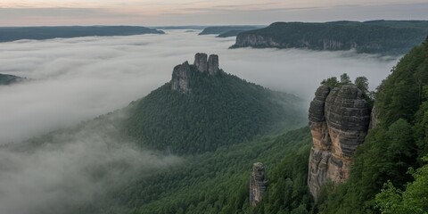 Monolithische Felsnadel ragt aus nebelverhangener Waldschlucht im Morgenlicht