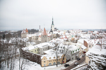 Snowy medieval cityscape of Tallinn, Estonia featuring St. Olaf's Church and defensive walls