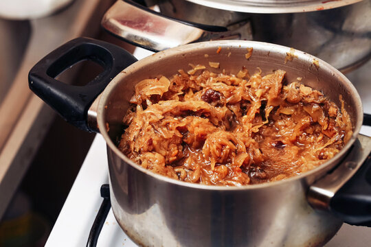 Traditional Polish bigos stew cooking in pot. Sauerkraut and meat simmered slowly. Christmas holiday meal preparation. Rustic home kitchen scene. Warm winter comfort food ready to serve.