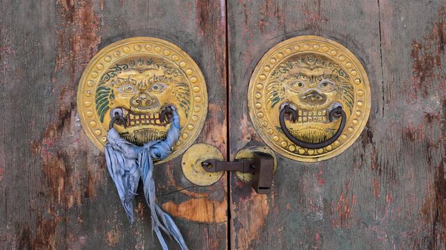 Detail of ornate brass door handles on a weathered wooden gate at Erdene Zuu Monastery in Kharkhorin, Mongolia. The oldest Buddhist temple in Mongolia features historic religious craftsmanship.
