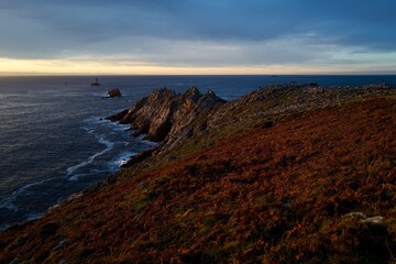Rugged coastal cliffs at sunset with warm autumn colors &mdash; dramatic seascape panorama with copy space