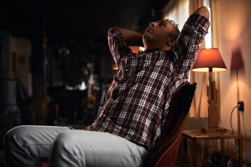 Man with headache, depression, sadness and loneliness sitting on a chair at home.