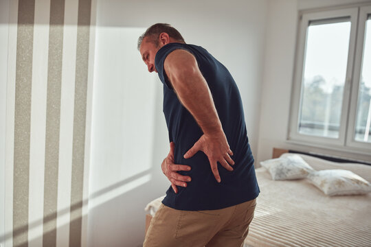 Man with hip, back, spine and sciatica pain at home.