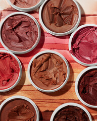 Collection of creamy cosmetic makeup pots displaying various richly pigmented shades of brown red and bronze