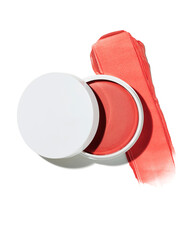 Creamy coral blush pot with an open white lid showcasing a vibrant swatch of shimmering makeup product