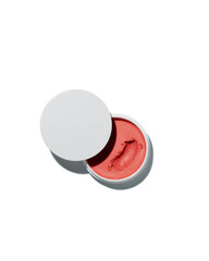 Open jar of creamy coral colored cosmetic balm product displays a textured swirl sample against a bright white background.