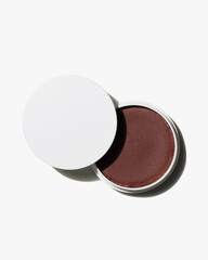 Minimalist white container of deep shimmering aubergine cream cosmetic product revealed against a bright white background studio shot