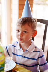 Child at table in party hat for birthday bash