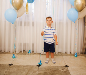 Young boy stands near balloons at a celebration event