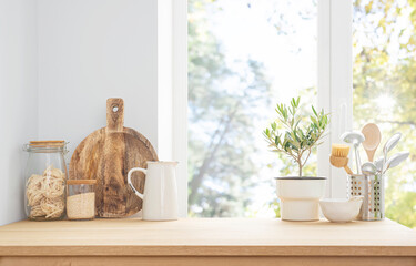 Kitchen utensils and cereals on wooden table near summer window in modern house interior with copy space