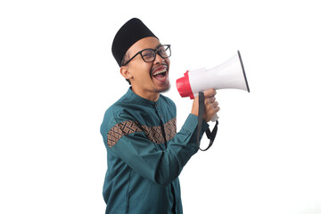 Fototapeta premium Excited Asian Muslim man in green traditional attire shouting into a megaphone. Isolated on white background. Concepts: Ramadan announcement, joyful celebration, special offer, limited-time deal.
