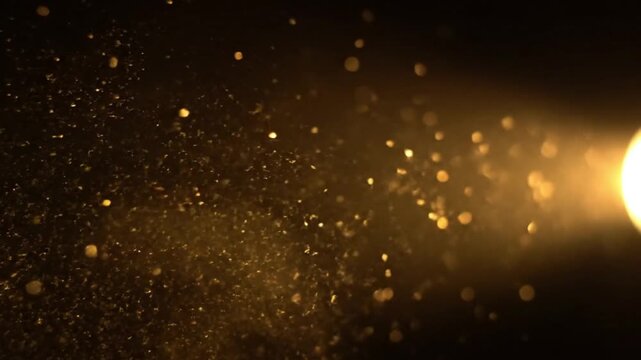 A mesmerizing cascade of golden, shimmering particles drifts gracefully through a warm, ethereal light beam, set against a dark, atmospheric backdrop. These glowing elements create a magical and elega