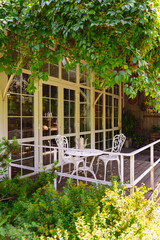 Outdoor seating area under green leaves near windows