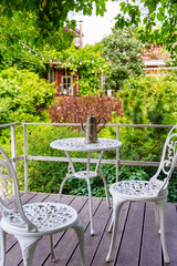 Table and chairs on a balcony surrounded by greenery