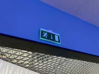 Green sign with reflective element depicting person running from building. Safe navigation in building during emergency or fire. Concept for rescuing and escaping burning building